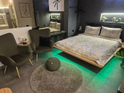 a bedroom with a bed and two chairs and a table at Biblioteka Spa Suite in Novi Beograd
