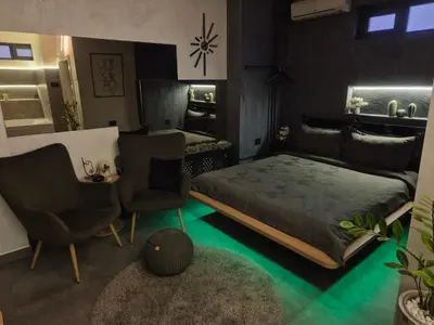 a bedroom with a bed and two chairs and a table at Biblioteka Spa Suite in Novi Beograd