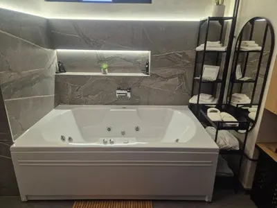 a bathroom with a large white tub in a room at Biblioteka Spa Suite in Novi Beograd
