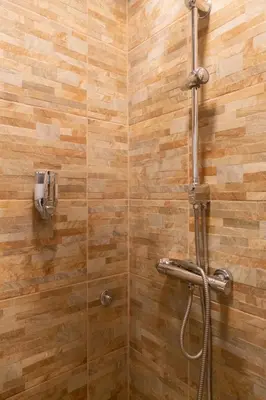 a bathroom with a shower with a wooden wall at Fair Apartment in Belgrade