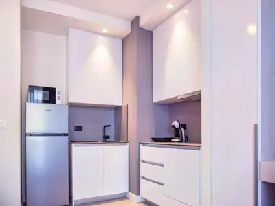 a kitchen with white cabinets and a refrigerator at Metropolitan Apartman - City View in Belgrade