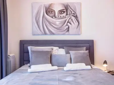 a painting of a woman is hanging above a bed at Metropolitan Apartman - City View in Belgrade