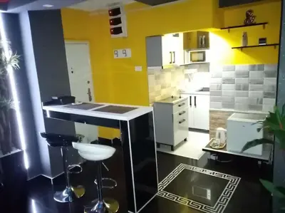 a kitchen with yellow walls and a counter with stools at Spa Apartment in Belgrade