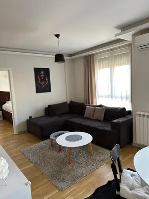 a living room with a black couch and a table at Apartman DM in Zvezdara