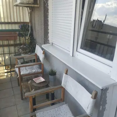 a balcony with two chairs and a table and a window at Apartman Centar in Belgrade