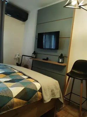 a bedroom with a bed and a flat screen tv on the wall at Studio Sunset in Voždovac