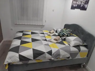 a bed with a checkered blanket and pillows on it at Tid Apartman in Arandjelovac