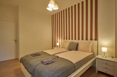 a bedroom with a large bed with a striped wall at Perfect 10 in Belgrade