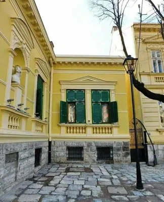 a yellow building with green windows and a street light at Globetrotter's City Center Pied-à-Terre ᯤ in Belgrade