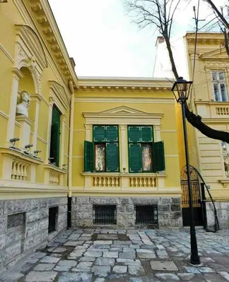 a yellow building with green windows and a street light at Globetrotter's City Center Modern ᯤ in Belgrade
