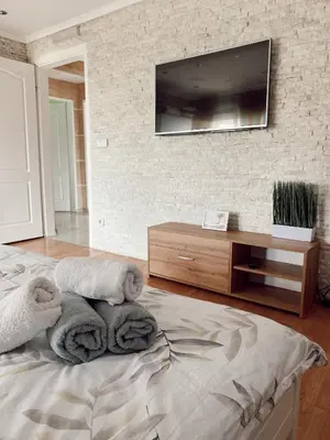 a bedroom with towels on a bed with a tv on the wall at Cozy Family House in Lazarevac
