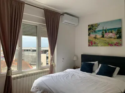 a bedroom with a bed and a large window at City Center Crown Apartment in Belgrade