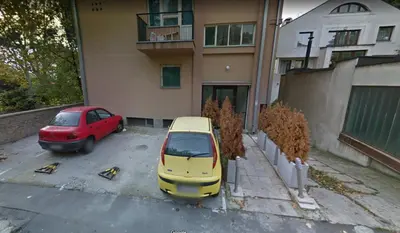 a yellow car parked in a parking lot in front of a building at Apartment Sofija Vracar in Belgrade