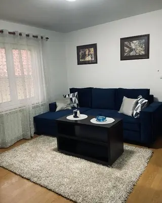 a living room with a blue couch and a coffee table at Apartman Bloom in Novi Grad