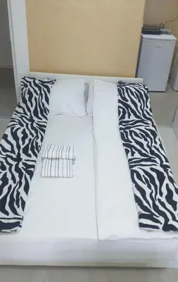 a white bed with black and white sheets and pillows at Apartman Marina Aranđelovac in Arandjelovac