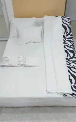 a bed with white sheets and pillows on it at Apartman Marina Aranđelovac in Arandjelovac
