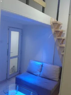 a living room with a blue couch and a staircase at Small Apartment FREE TRANSPORTATION FROM THE AIRPORT TO THE APARTMENT in Belgrade