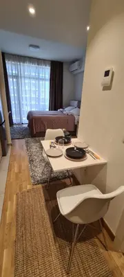 a living room with a table and a bed at Premium Studio Apartment - Belgrade Waterfront in Sajmište