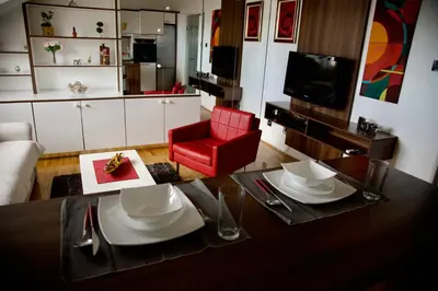 a living room with a table and a red chair at TRIANGLE CITY Apartment 1 in Belgrade