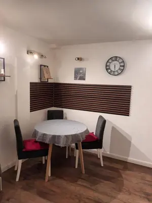 a table and chairs in a room with a clock on the wall at Aurora in Zvezdara