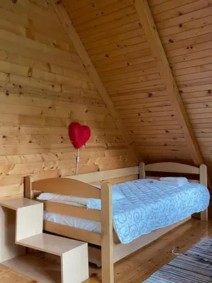 a bed in a wooden room with a heart balloon at Brvnara oaza mira - Devojacki bunar in Alibunar