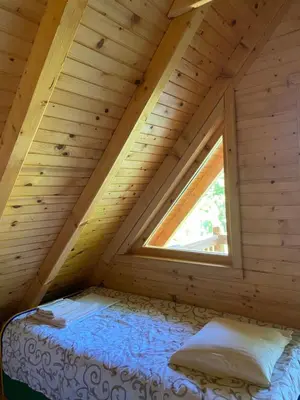 a bed in a wooden room with a window at Brvnara oaza mira - Devojacki bunar in Alibunar