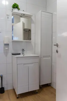 a white bathroom with a sink and a mirror at Siva in Fontana