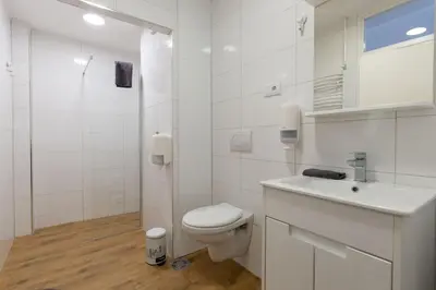 a white bathroom with a toilet and a sink at Siva in Fontana