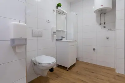 a white bathroom with a toilet and a sink at Siva in Fontana