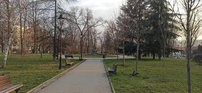 a path in a park with benches and trees at Belgrade St Sava Temple Hram in Belgrade