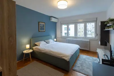 a bedroom with a bed with a blue wall at Belgrade Center Apartment in Belgrade