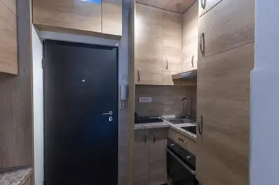 a black door in a kitchen with wooden cabinets at Belgrade Center Apartment in Belgrade