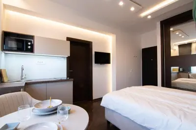 a bedroom with a bed and a table and a kitchen at Square 6 in Belgrade