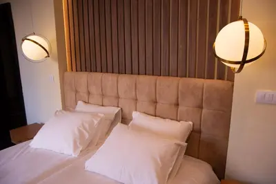 a bedroom with a bed with white pillows and two lights at Square 6 in Belgrade