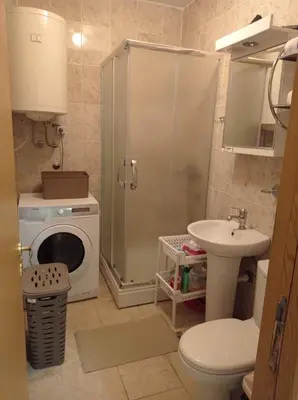 a bathroom with a shower and a sink and a washing machine at NMD Apartments in Zvezdara