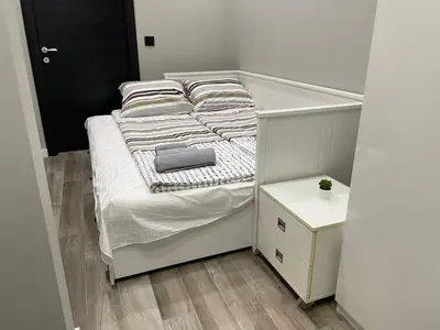 a small white bed in a room with a night stand at Alisa Novi Beograd in Bežanija