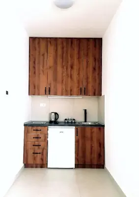 a kitchen with wooden cabinets and a white refrigerator at Apartman Kedar in Arandjelovac