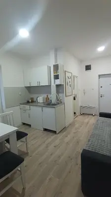 a kitchen with white cabinets and a wooden floor at Gepratova Apartment in Belgrade
