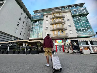 a man is pulling a suitcase in front of a building at Most apartman in Ruma