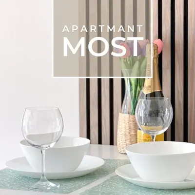 a bottle of wine and two glasses on a table at Most apartman in Ruma