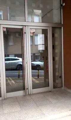 two glass doors of a building with a reflection of a street at Glorry M in Belgrade