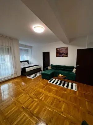 a living room with a green couch and a bed at Biser in Filmski Grad