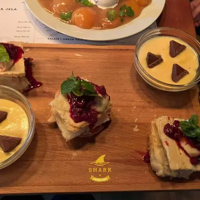 a wooden cutting board topped with sandwiches and desserts at Biser in Filmski Grad