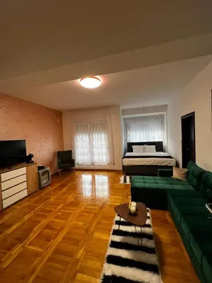 a living room with a green couch and a bed at Biser in Filmski Grad