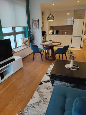 a living room with a blue couch and a kitchen at 2-Bedroom Oasis in the heart of the Waterfront in Sajmište