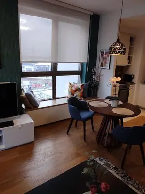 a living room with a table and a large window at 2-Bedroom Oasis in the heart of the Waterfront in Sajmište