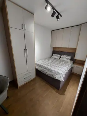 a small bedroom with a bed and white cabinets at Apartman M 21 in Karaburma