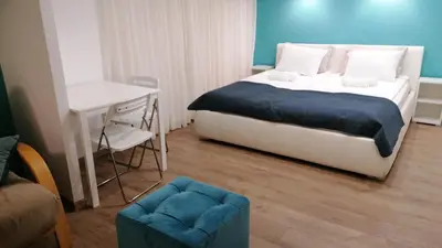 a bedroom with a bed and a table and a desk at Apartman Dunja S in Belgrade