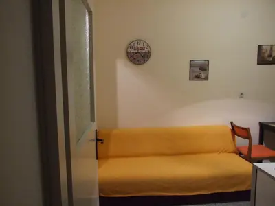 a yellow couch in a room with a clock on the wall at Georgina in Rospi Ćuprija