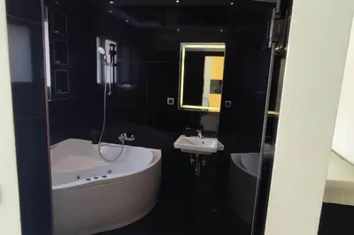 a black bathroom with a tub and a sink at Lux Spa Apartman na Vračaru in Vračar (historical)